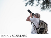 Asian traveler man with backpack taking a photo in the park with copy space. Travel photographer. Vocation and holiday concept. Стоковое фото, агентство Ingram Publishing / Фотобанк Лори