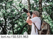 Asian traveler man with backpack taking a photo in the park with copy space. Travel photographer. Vocation and holiday concept. Стоковое фото, агентство Ingram Publishing / Фотобанк Лори