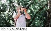 Asian traveler man with backpack taking a photo in the park. Travel photographer. Vocation and holiday concept. Стоковое фото, агентство Ingram Publishing / Фотобанк Лори