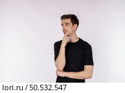 Portrait of young man thinking touching chin isolated over white background. Thinking worried about a question, concerned and nervous with hand on chin. Стоковое фото, агентство Ingram Publishing / Фотобанк Лори