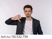 Portrait of young businessman shows sign of dislike, looks with negative expression and disapproval on isolated background. Disagreement, disgust and negative expressions. Стоковое фото, агентство Ingram Publishing / Фотобанк Лори