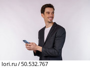 Portrait of a happy businessman using smartphone over white background. Using mobile phone, typing sms message. Стоковое фото, агентство Ingram Publishing / Фотобанк Лори