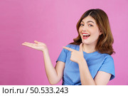 Portrait of excited young woman wearing casual t-shirt hold hand demonstrate offer ads promo isolated over pink background. Expression, people and lifestyle concept. Стоковое фото, агентство Ingram Publishing / Фотобанк Лори