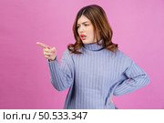 Portrait of angry sad young woman point index finger aside isolated over pink background. People lifestyle and emotion concept. Стоковое фото, агентство Ingram Publishing / Фотобанк Лори