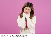 Portrait of beautiful young woman holding hands under chin and looking at something isolated over pink background. People lifestyle concept. Стоковое фото, агентство Ingram Publishing / Фотобанк Лори