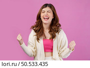 Portrait close-up of cheerful positive young woman standing and making winner gesture isolated over pink background. Life people energy and success concept. Стоковое фото, агентство Ingram Publishing / Фотобанк Лори