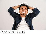 Portrait of Disappointed young asian man in blue shirt annoyed angry in furious gesture isolated on white background. Expression and lifestyle concept. Стоковое фото, агентство Ingram Publishing / Фотобанк Лори