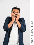 Portrait of Disappointed young asian man in blue shirt annoyed angry in furious gesture isolated on white background. Expression and lifestyle concept. Стоковое фото, агентство Ingram Publishing / Фотобанк Лори