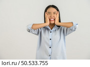 Portrait of Attractive shocked young asian woman in blue shirt isolated on white background. Expression and lifestyle concept. Стоковое фото, агентство Ingram Publishing / Фотобанк Лори