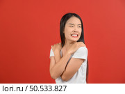 Portrait of Young asian woman in white t-shirt hugging oneself happy and positive isolated on red background. Expression and lifestyle concept. Стоковое фото, агентство Ingram Publishing / Фотобанк Лори