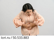 Portrait of Young asian woman in pink shirt stomach ache isolated on white background. Expression and lifestyle concept. Стоковое фото, агентство Ingram Publishing / Фотобанк Лори
