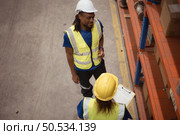 High angle view of warehouse workers in hardhats lifting boxes at warehouse. Стоковое фото, агентство Ingram Publishing / Фотобанк Лори