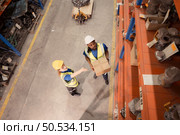 High angle view of warehouse workers in hardhats lifting boxes at warehouse. Стоковое фото, агентство Ingram Publishing / Фотобанк Лори