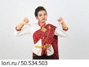 Portrait young pretty woman dress up in beautiful  local culture in northern region with gladtful posture, grimace and thumb down on white background, copy space. Стоковое фото, агентство Ingram Publishing / Фотобанк Лори