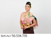 Portrait asian pretty woman posing with smiling in Thai northeastern dress costume,  Welcome expression Sawasdee on white background. Стоковое фото, агентство Ingram Publishing / Фотобанк Лори
