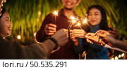 Portrait of Happy Asian group of friends having fun with sparklers outdoor - Young people having fun with fireworks at night time  - People, food, drink lifestyle, new year celebration concept. Стоковое фото, агентство Ingram Publishing / Фотобанк Лори