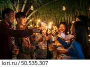 Portrait of Happy Asian group of friends having fun with sparklers outdoor - Young people having fun with fireworks at night time  - People, food, drink lifestyle, new year celebration concept. Стоковое фото, агентство Ingram Publishing / Фотобанк Лори