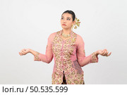 Young beautiful woman dress up in local culture in southern region, standing open palms and grimace with upset posture on white background, copy space. Стоковое фото, агентство Ingram Publishing / Фотобанк Лори