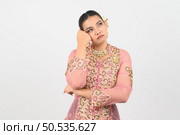 Young beautiful woman dress up in local culture in southern region with thoughtful posture on white background, copy space. Стоковое фото, агентство Ingram Publishing / Фотобанк Лори