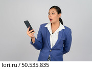 Portrait Asian young woman in officer uniform standing with mobile phone in hand posture, Cheerful girl with happy smiling during use smartphone, isolated on white background. Стоковое фото, агентство Ingram Publishing / Фотобанк Лори