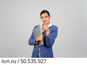 Portrait Asian young woman in officer uniform point finger and hold laptop computer in hand posture,  Pretty girl grimace with upset isolated on white background. Стоковое фото, агентство Ingram Publishing / Фотобанк Лори
