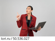 Portrait Asian young woman in officer uniform holding laptop computer with wireless earphone posture, Cheerful girl happy smiling during working with technology device, isolated on white background. Стоковое фото, агентство Ingram Publishing / Фотобанк Лори