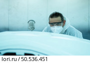 Auto mechanic in car spray room Inspecting the paint sprayed into the front bumper of the car that the pigment is complete, beautiful, harmonious with the original color of the car. Стоковое фото, агентство Ingram Publishing / Фотобанк Лори