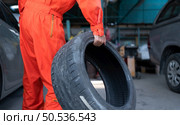 A car mechanic inspects the condition of a car tire before placing it on a vehicle. Стоковое фото, агентство Ingram Publishing / Фотобанк Лори