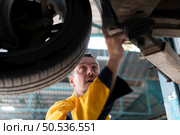 Auto repair mechanic the undercarriage of the car is being inspected for damage caused by heavy collisions. Стоковое фото, агентство Ingram Publishing / Фотобанк Лори