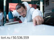 Auto mechanic use an electric polisher to polish the dried car paint. After passing the paint from the car painting room. Стоковое фото, агентство Ingram Publishing / Фотобанк Лори