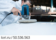 Auto mechanic use an electric polisher to polish the dried car paint. After passing the paint from the car painting room. Стоковое фото, агентство Ingram Publishing / Фотобанк Лори