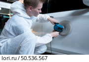 Auto mechanic use an electric polisher to polish the dried car paint. After passing the paint from the car painting room. Стоковое фото, агентство Ingram Publishing / Фотобанк Лори