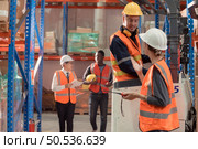 Managers, foremen and warehouse workers Consult together about getting the goods out of the warehouse to finish sending the small merchants tonight. Стоковое фото, агентство Ingram Publishing / Фотобанк Лори