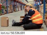 A warehouse employee was injured in an accident. because the product package fell from the shelves and crushed the employee’s leg severely. Стоковое фото, агентство Ingram Publishing / Фотобанк Лори