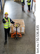 Worker in auto parts warehouse use a handcart to work to bring the box of auto parts into the storage shelf of the warehouse waiting for delivery to the car assembly line. Стоковое фото, агентство Ingram Publishing / Фотобанк Лори