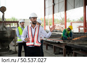 Group of architects, construction foremen, and construction engineers review the work and talk about how the project, in the construction site. Стоковое фото, агентство Ingram Publishing / Фотобанк Лори