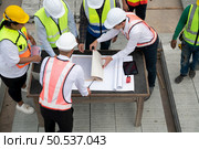 Construction engineers, architects, and foremen form a group. Participate in a meeting to plan new construction projects. Стоковое фото, агентство Ingram Publishing / Фотобанк Лори