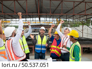 Construction engineers, architects, and foremen form a group. Participate in a meeting to plan new construction projects. Cheers to express happiness that the event was successfully accomplished. Стоковое фото, агентство Ingram Publishing / Фотобанк Лори
