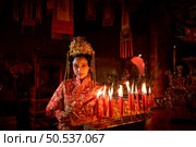 Chinese woman make wishes, pray, and light candles. On the occasion of the annual Chinese New Year festival, in a revered shrine or temple, And in Chinese where candles mean good luck and happiness. Стоковое фото, агентство Ingram Publishing / Фотобанк Лори
