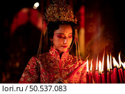 Chinese woman make wishes, pray, and light candles. On the occasion of the annual Chinese New Year festival, in a revered shrine or temple, And in Chinese where candles mean good luck and happiness. Стоковое фото, агентство Ingram Publishing / Фотобанк Лори