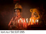Chinese woman make wishes, pray, and light candles. On the occasion of the annual Chinese New Year festival, in a revered shrine or temple, And in Chinese where candles mean good luck and happiness. Стоковое фото, агентство Ingram Publishing / Фотобанк Лори