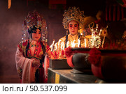 Male and female Chinese opera actors Light a candle to pray homage to the gods to enhance the prosperity for yourself on the occasion of the Chinese New Year festival. Стоковое фото, агентство Ingram Publishing / Фотобанк Лори
