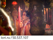 Chinese woman make wishes, pray, and light candles. On the occasion of the annual Chinese New Year festival, in a revered shrine or temple, And in Chinese where candles mean good luck and happiness. Стоковое фото, агентство Ingram Publishing / Фотобанк Лори