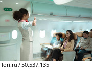 Flight attendants show how to use safety devices and recommend emergency exits. Стоковое фото, агентство Ingram Publishing / Фотобанк Лори