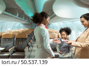 Flight attendant greet passengers as they enter the aircraft to locate a seat in the cabin. Стоковое фото, агентство Ingram Publishing / Фотобанк Лори