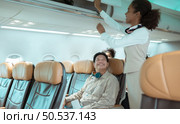 Flight attendant check the order of the passenger’s luggage storage. Стоковое фото, агентство Ingram Publishing / Фотобанк Лори
