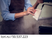 By cleaning it with a clean cloth and activating the steam to discharge the empty milk frother, the barista cleans the milk frother. Стоковое фото, агентство Ingram Publishing / Фотобанк Лори