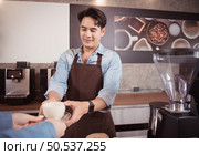 Young barista with the intention of making up a latte coffee to satisfy customers both in appearance and taste, This cup of coffee is ready to be served. Стоковое фото, агентство Ingram Publishing / Фотобанк Лори