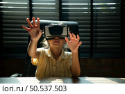 Portrait of little girl in office room of house with gestures that are expressed when playing virtual reality games. Стоковое фото, агентство Ingram Publishing / Фотобанк Лори