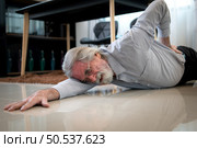 The old man fell down in the living room inside the house. have to take care of themselves without their children taking care of them have severe back pain. Стоковое фото, агентство Ingram Publishing / Фотобанк Лори